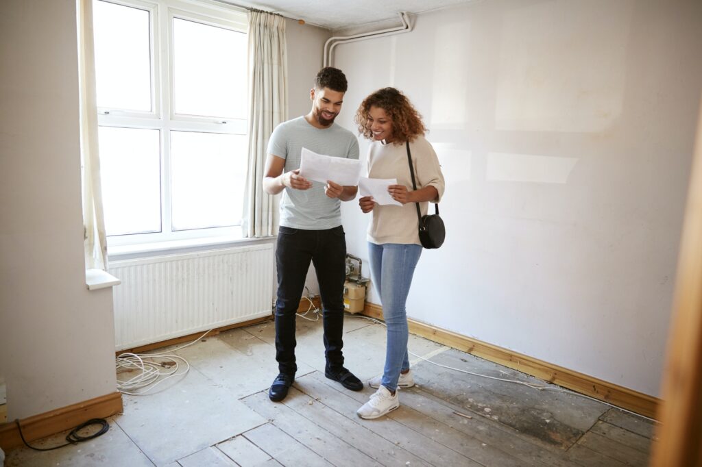 couple buying house for first time looking at house survey in room to be renovated